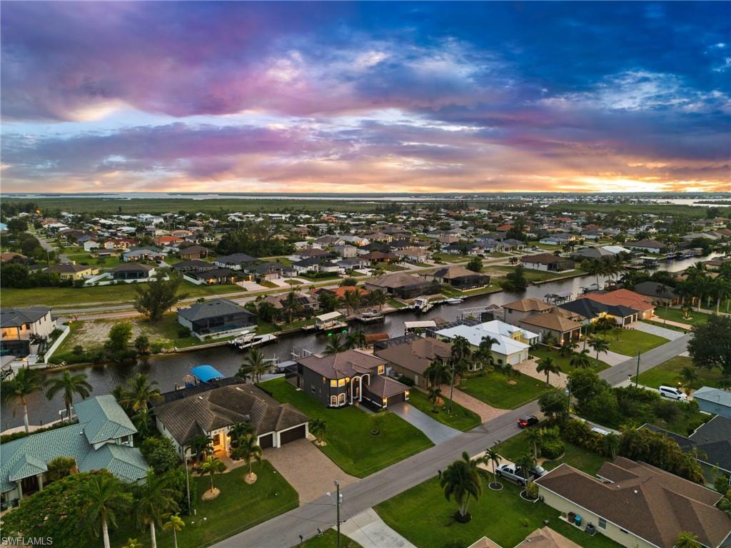 Sweeping aerial view highlights the surrounding Cape Coral canal community, waterfront residences, private docks, and broader Southwest Florida landscape. This perspective provides useful context for buyers evaluating the home's location and boating environment.