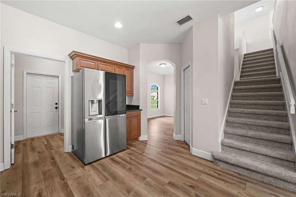 Kitchen view highlights the stainless LG refrigerator, surrounding cabinetry, nearby storage, and convenient access to the staircase and adjoining first-floor spaces. The appliance package is among the property's documented recent upgrades.