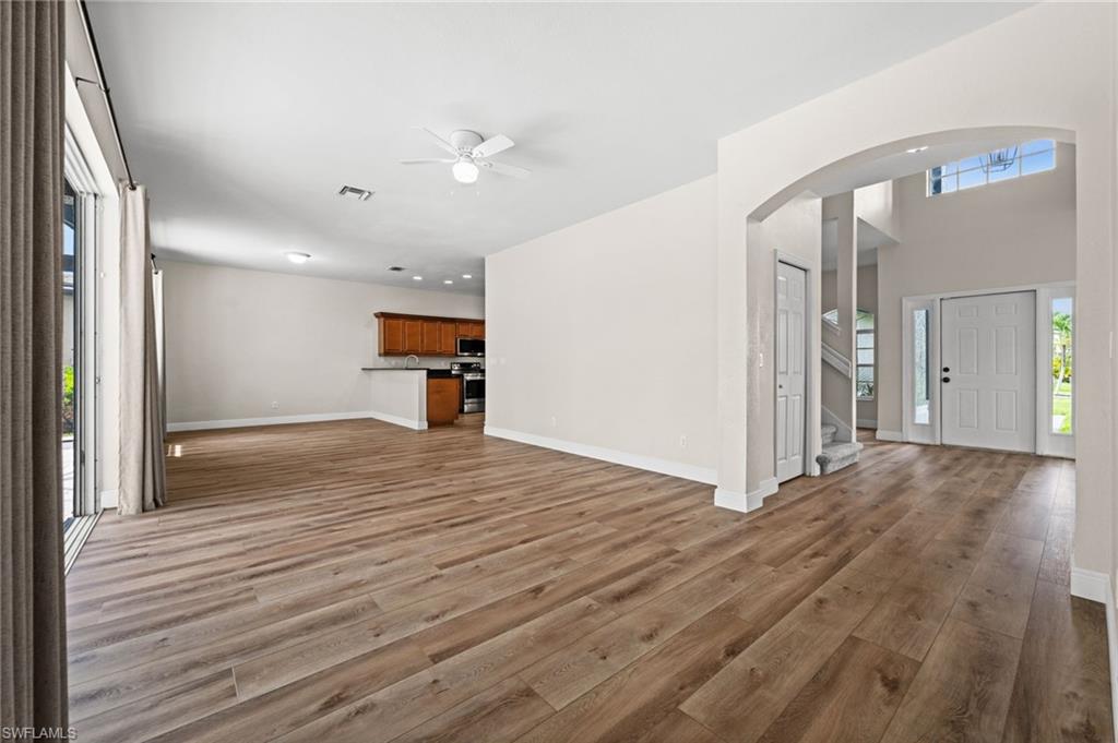 Expansive main living area showcases the open-concept floor plan with easy connection to the kitchen, entry, and outdoor living spaces. Wood-look flooring and neutral finishes create a versatile backdrop for furnishings and décor.