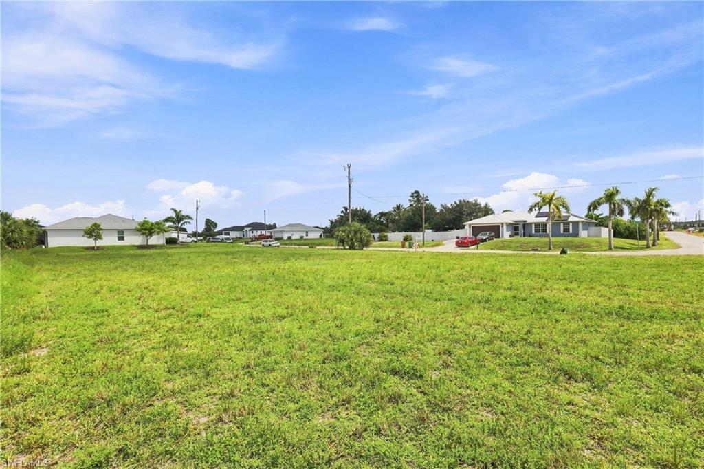 Expansive open lot with natural grass and a clear blue sky