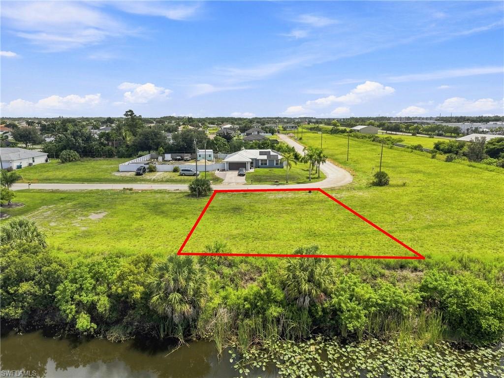 Expansive lot with direct water frontage, featuring lush green landscaping and mature tropical foliage
