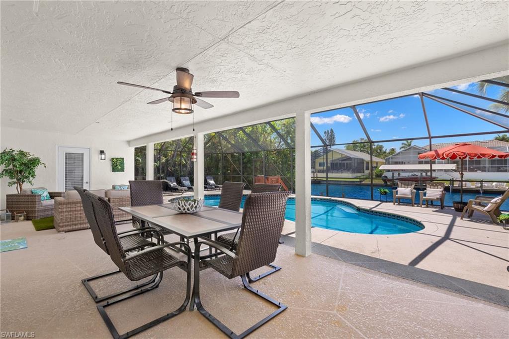 View of swimming pool with a patio area, glass enclosure, ceiling fan, and an outdoor living space