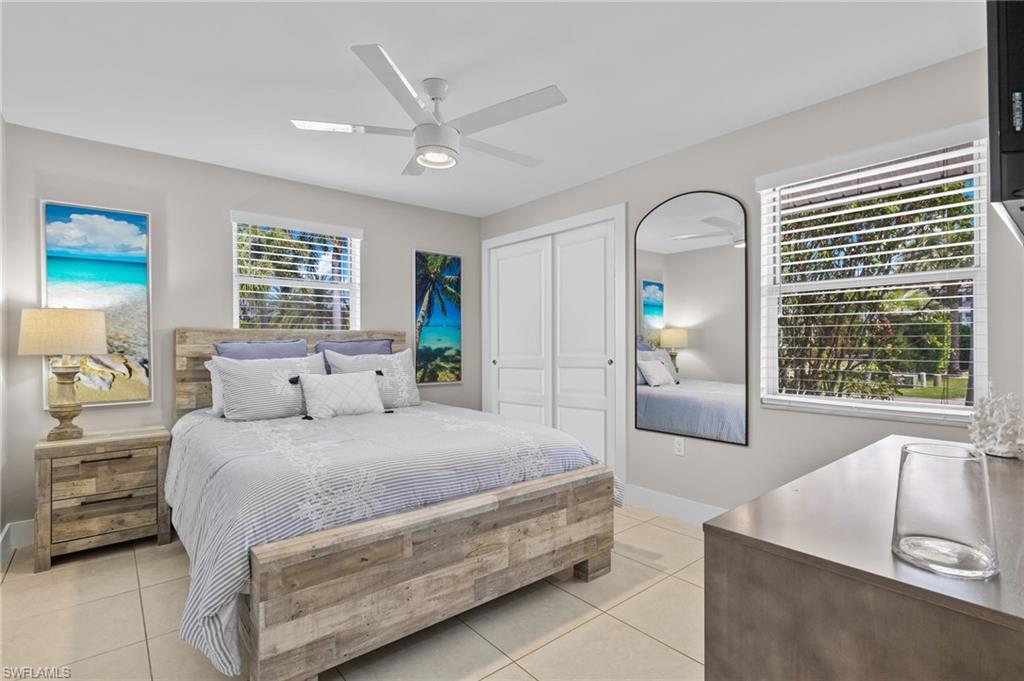 Bedroom with ceiling fan, light tile floors, and multiple windows