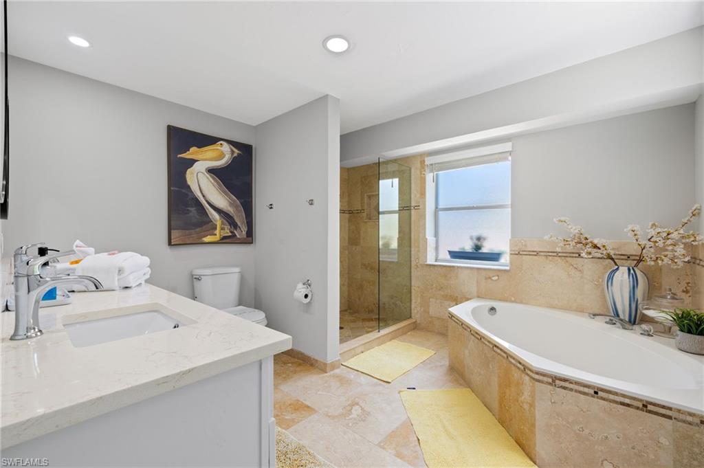 Full bathroom with tile flooring, vanity, toilet, and plus walk in shower