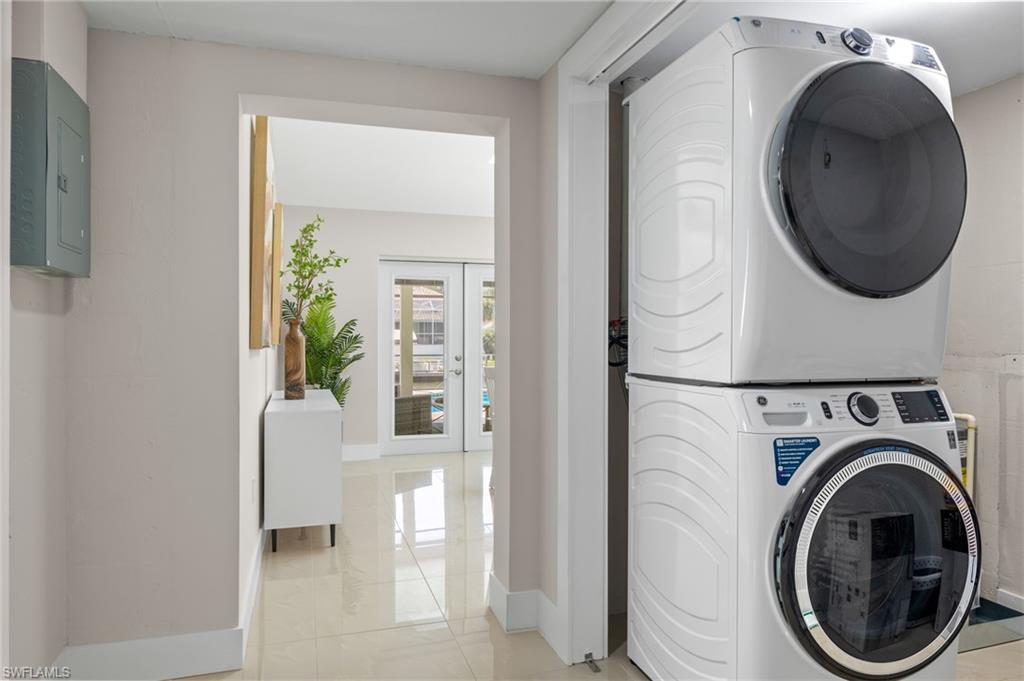 Washroom featuring stacked washing maching and dryer and light tile floors