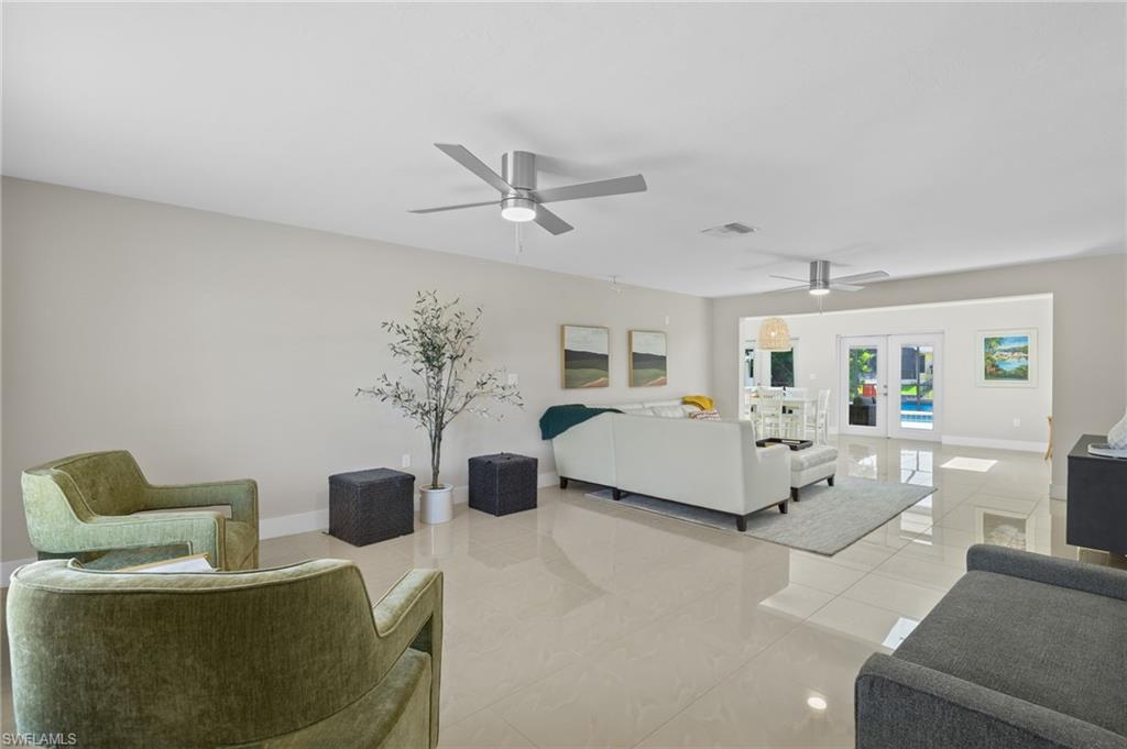 Living room with ceiling fan, french doors, and light tile floors