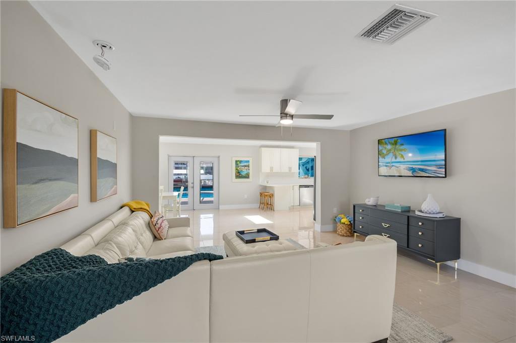 Tiled living room featuring french doors and ceiling fan
