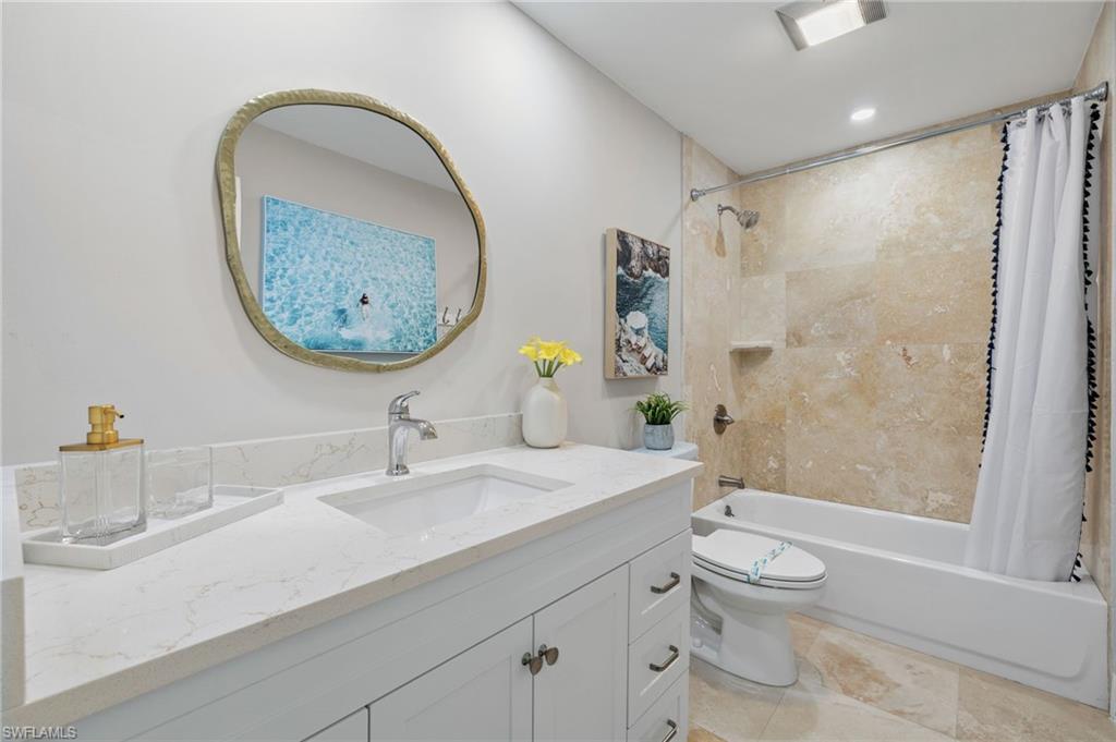 Full bathroom featuring shower / bathtub combination with curtain, vanity, toilet, and tile floors