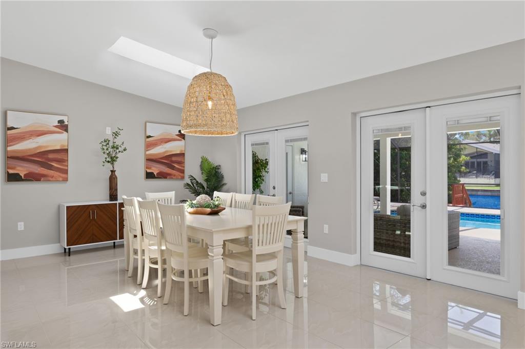 Dining area with french doors, light tile flooring, and lofted ceiling with skylight