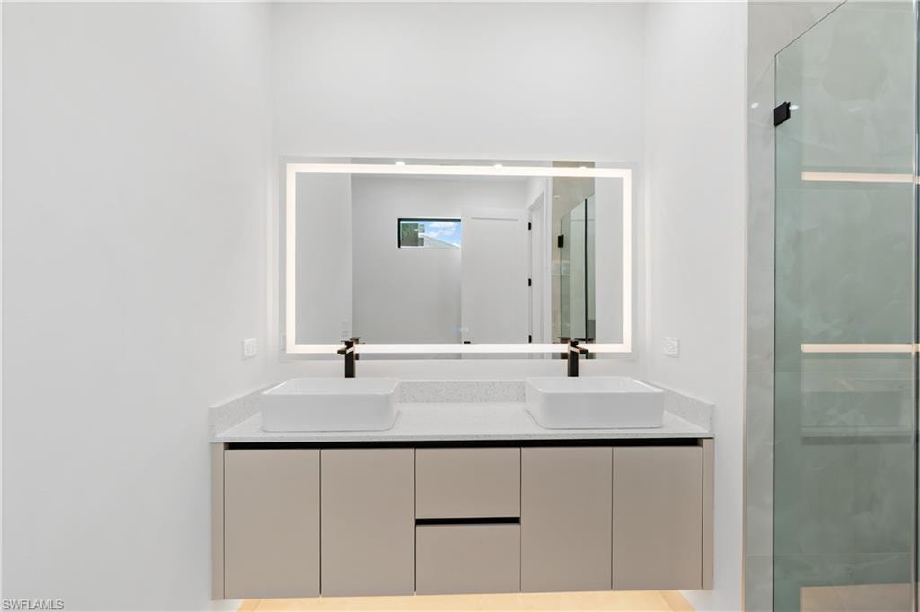 Floating dual vanity with two rectangular vessel sinks, matte black faucets, and a light-framed mirror