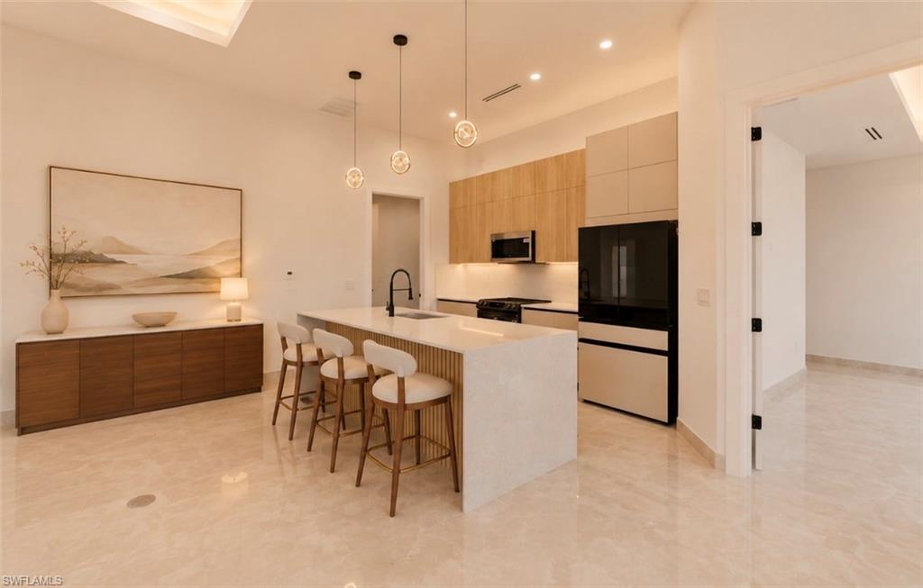 Gourmet kitchen with island seating, stainless steel appliances, wood-finish cabinetry, and recessed lighting