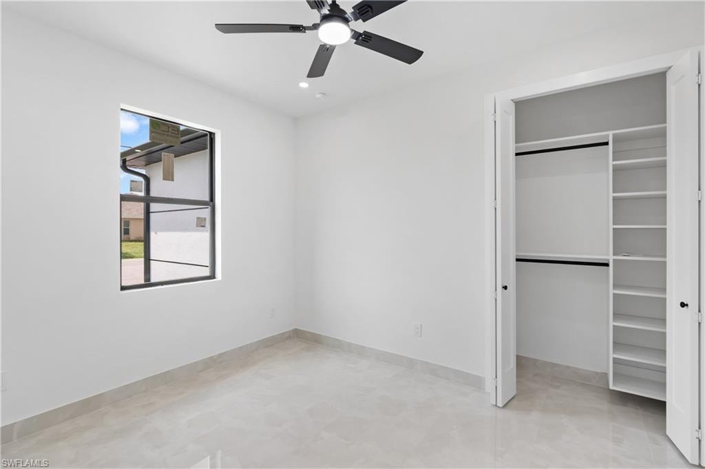 Recessed lighting, ceiling fan with light fixture, large window, built-in closet shelving, and tile flooring