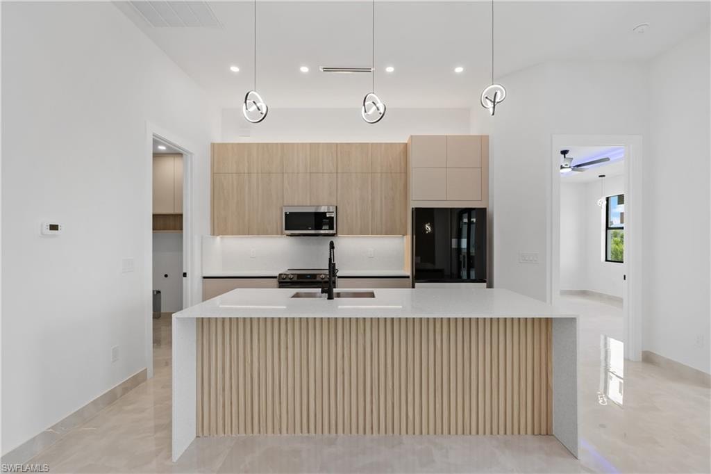 Kitchen featuring a waterfall island with slatted wood-finish paneling, white countertop, and contemporary pendant lighting