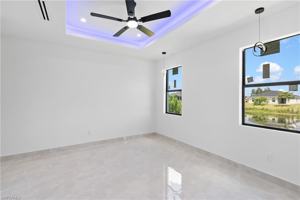 Recessed lighting, contemporary ceiling fan, tray ceiling with accent lighting, large windows, and tile flooring