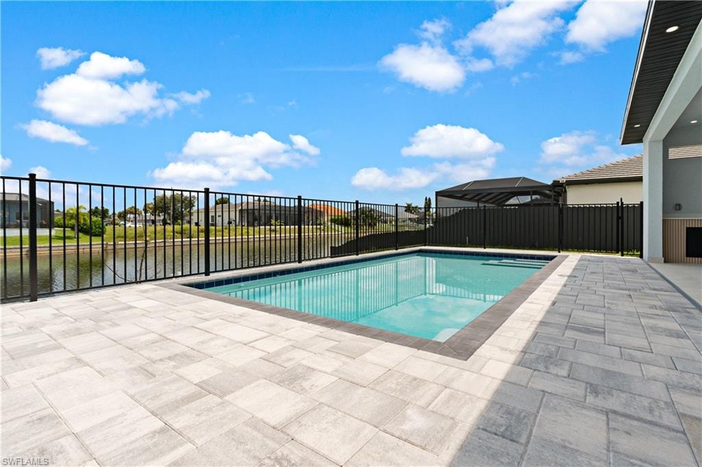 Rectangular pool with paver decking and a black metal fence