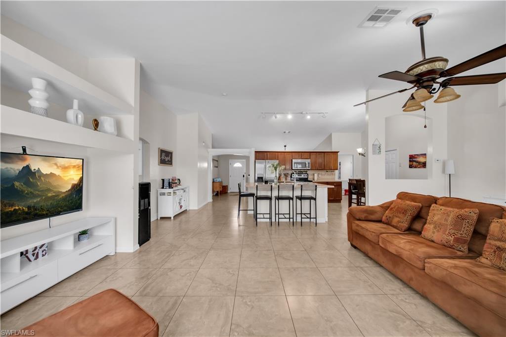 Open-concept living area featuring tile flooring, built-in shelving, and a ceiling fan