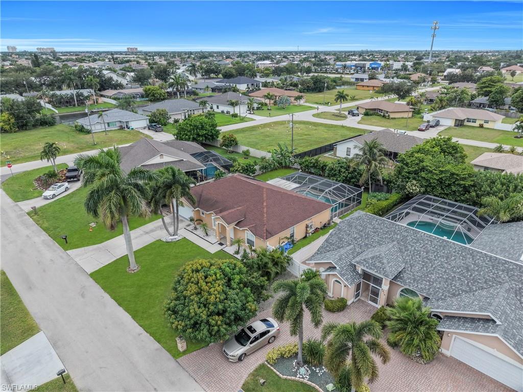 Single-story residence featuring a shingled roof, paved driveway, and established landscaping