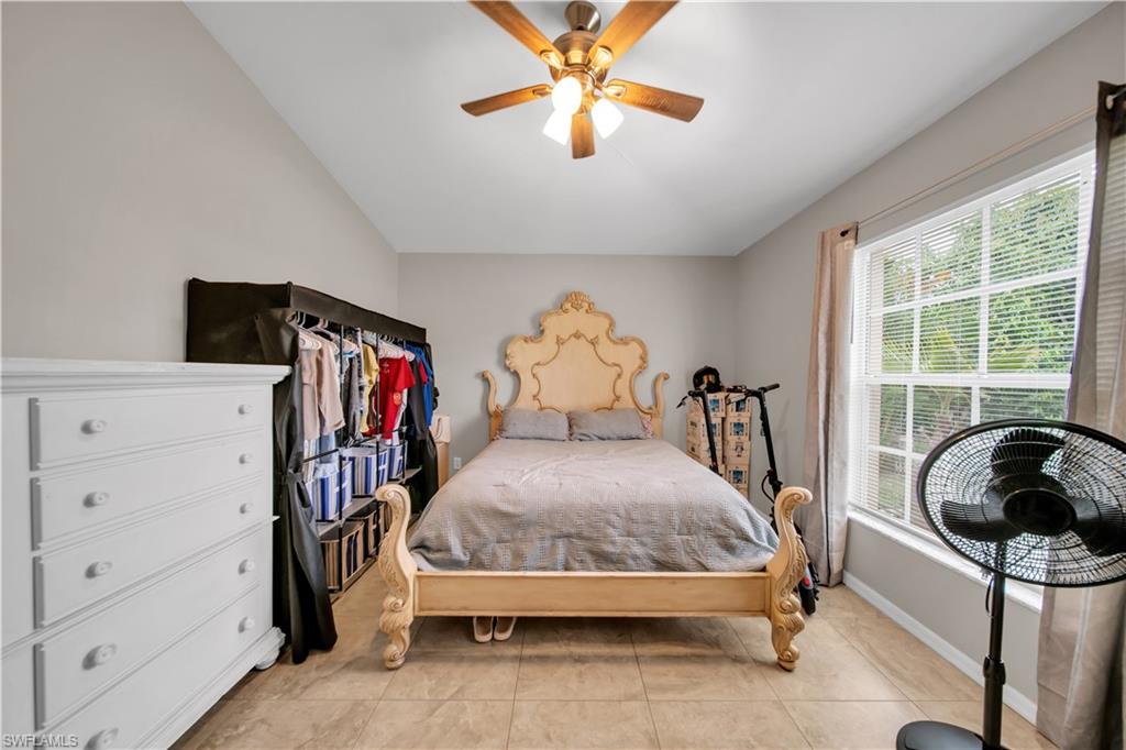 Vaulted ceiling with a ceiling fan, window with horizontal blinds, and tile flooring