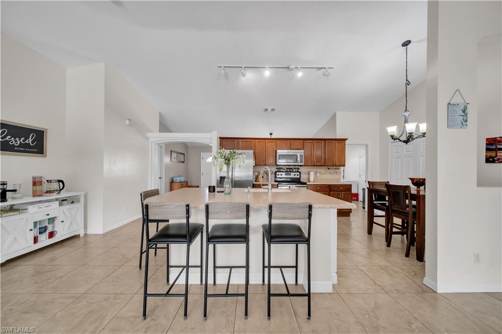 Kitchen featuring an island with seating, a stainless steel sink, wood cabinetry, and a tile backsplash