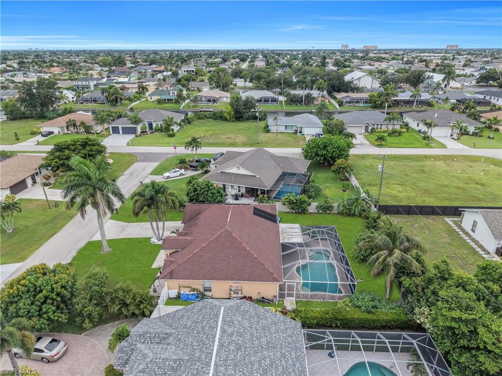 Expansive residential neighborhood featuring single-story homes with shingle roofs, private swimming pools, and mature palm trees