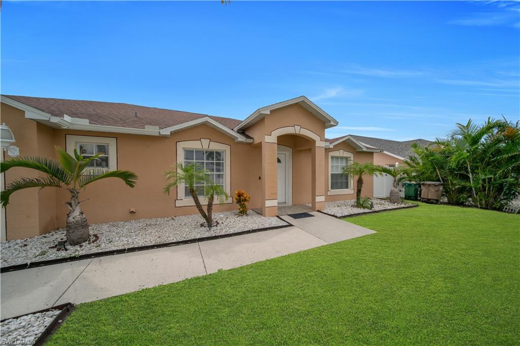 Stucco exterior with arched entry, gabled roofline, and white-framed windows