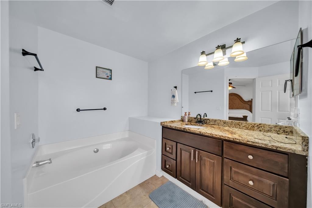 Soaking tub with chrome fixtures, wood-finish vanity with stone countertop, and an integrated basin sink