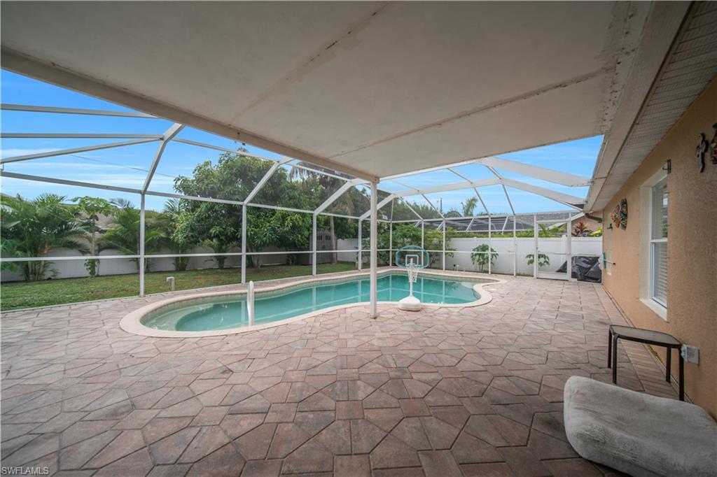 Screened enclosure encompassing a freeform pool, integrated spa, and extensive paver patio