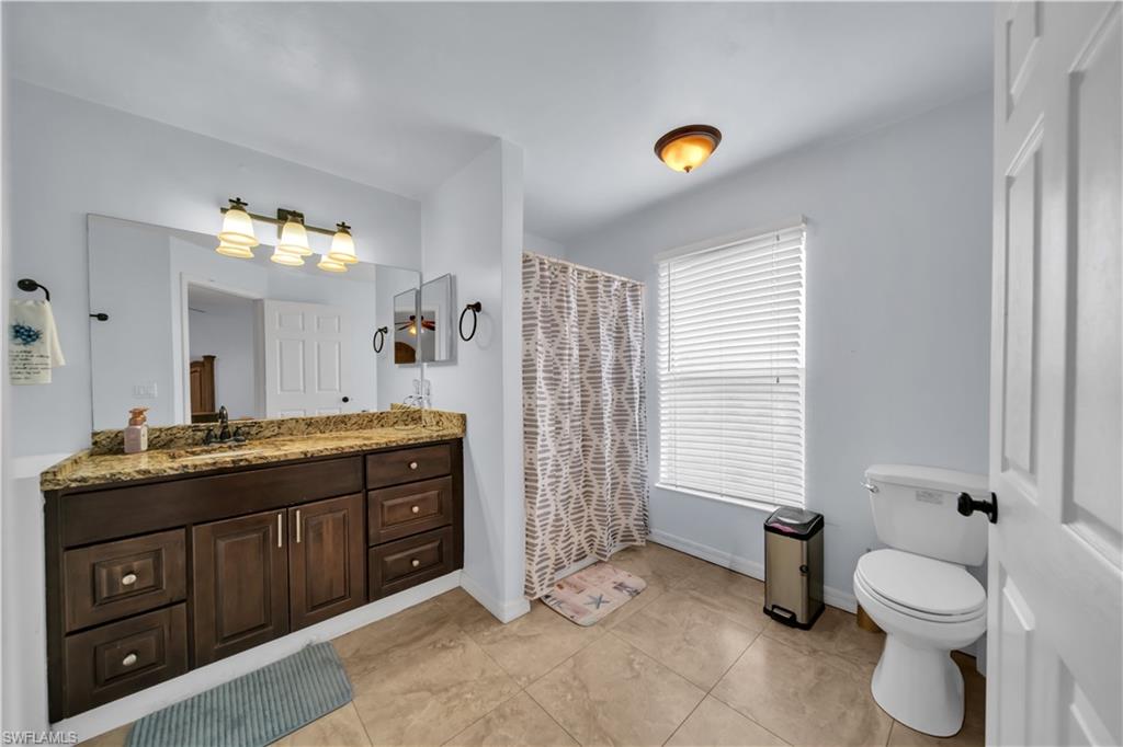 Expansive vanity with a stone countertop, a large mirror, and a three-light fixture