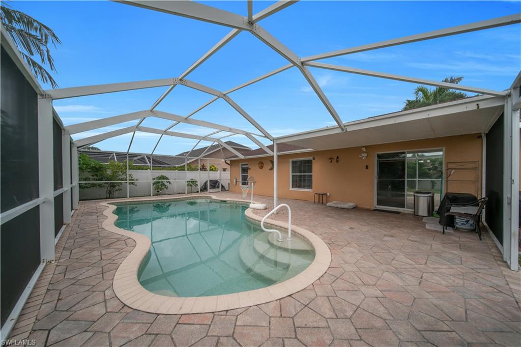 Screened-in outdoor living space with a freeform swimming pool, integrated steps, and paver decking