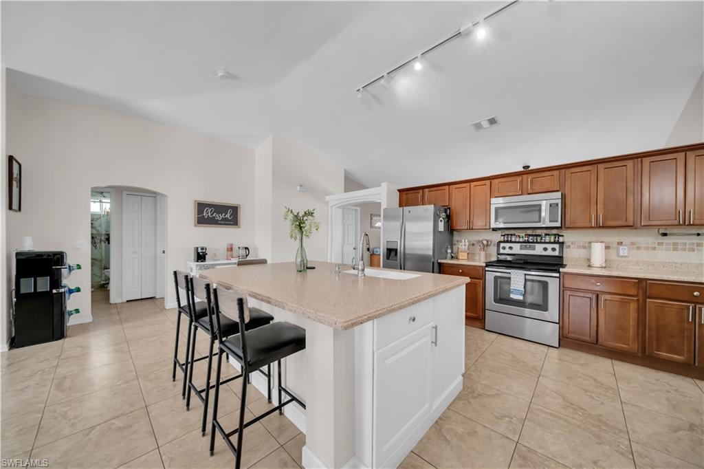Kitchen featuring a central island with countertop seating, stainless steel appliances, wood cabinetry, and tiled flooring