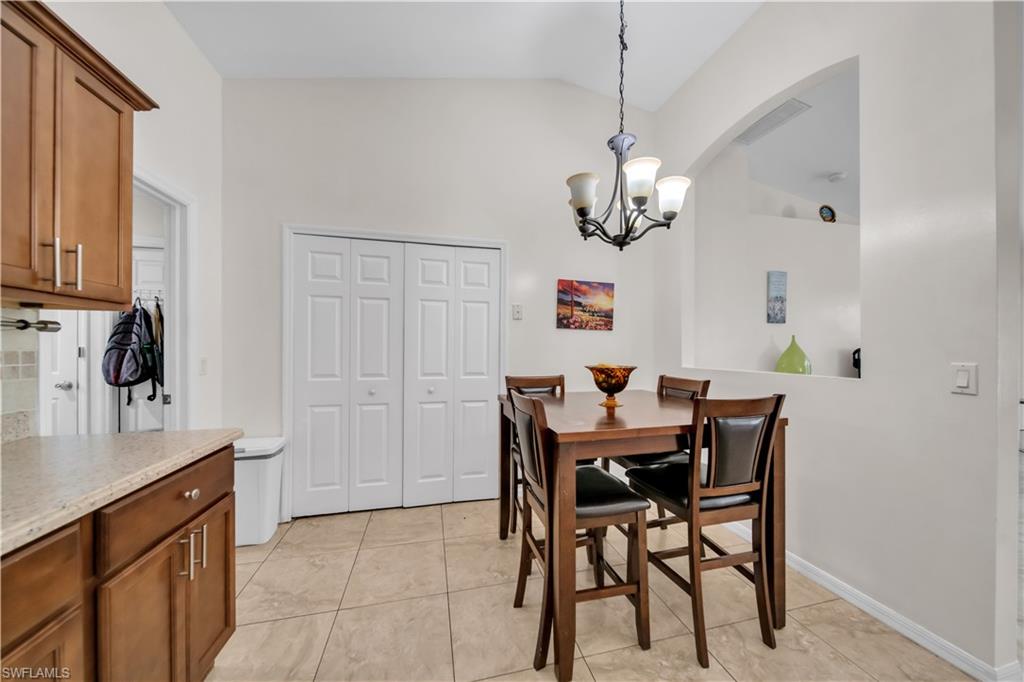 Vaulted ceiling with an attached chandelier, archway feature, bi-fold doors, and a tiled floor