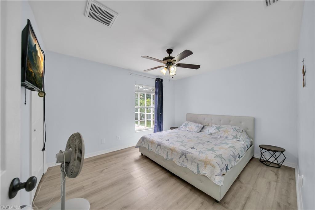 White walls with wood-finish flooring, a ceiling fan with integrated lighting, and a multi-pane window