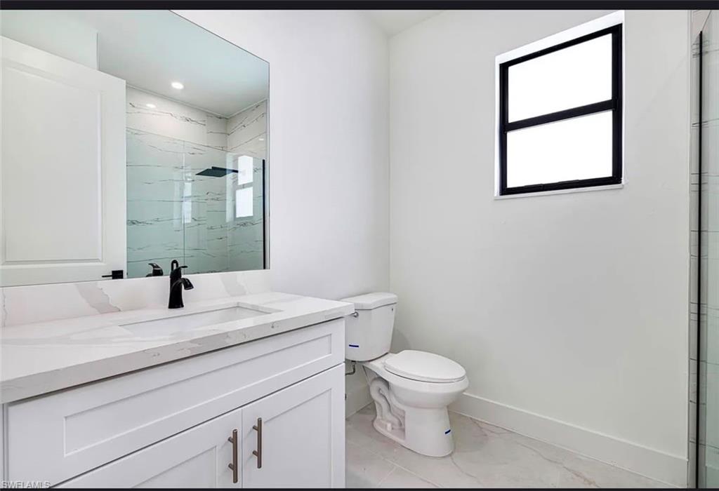 Vanity with a white countertop and integrated sink, matte black faucet, wall-mounted mirror, and white cabinetry with brushed nickel hardware