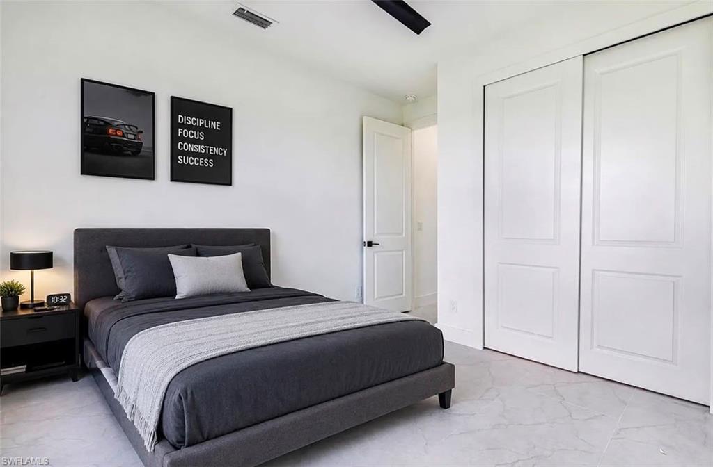 White walls, ceiling fan, and light-toned flooring