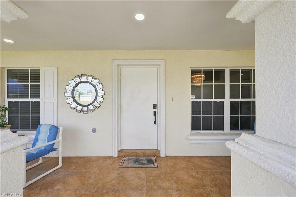 Covered porch with recessed lighting, textured exterior walls, white entry door with black hardware, and two windows featuring white frames