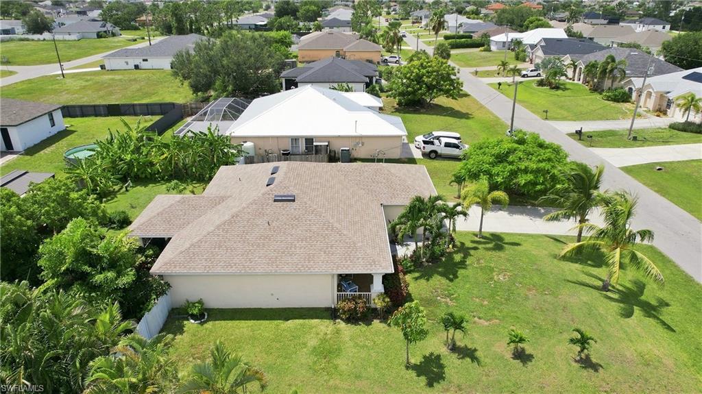 Spacious property with a light-colored shingle roof, established landscaping, and a manicured lawn