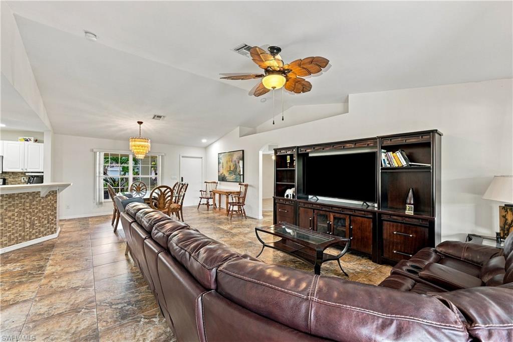 Vaulted ceilings, tile flooring, built-in entertainment center, breakfast bar with stone mosaic accent, and a dining area with pendant lighting