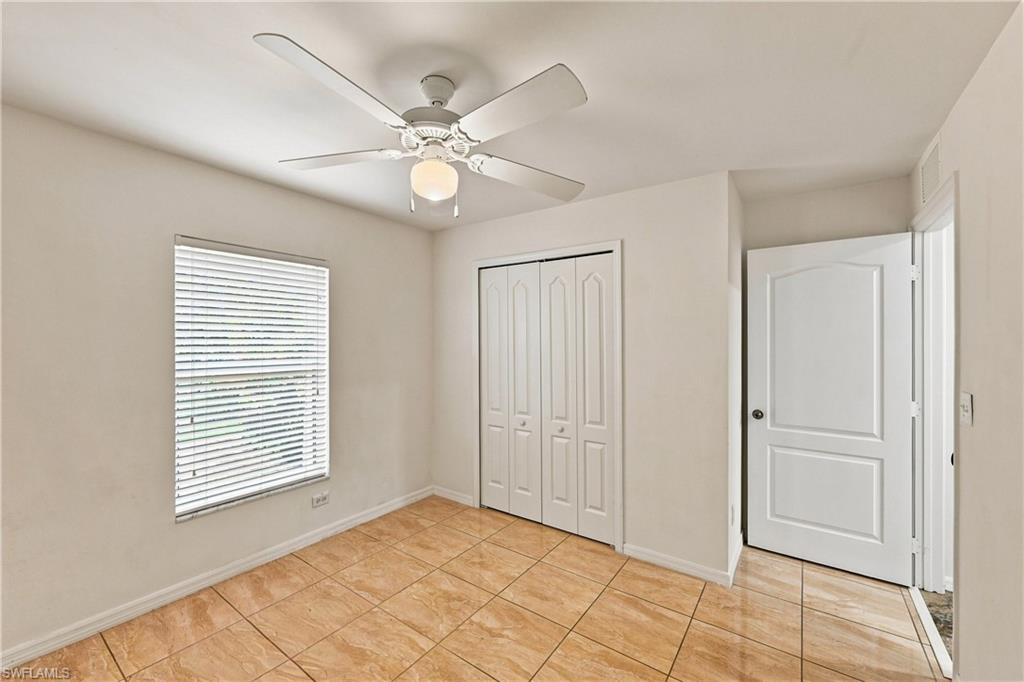 Neutral-toned walls complement the tile flooring, while a window with blinds offers natural light