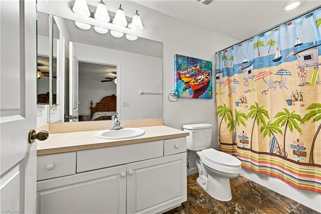 Bathroom featuring a single vanity with an integrated sink, white cabinetry, a large wall-mounted mirror, and dark-toned flooring