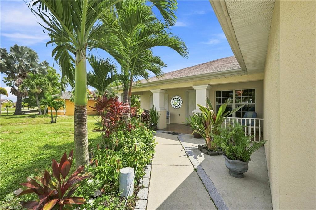 Exterior featuring a stucco finish, covered entryway, column accents, multiple window panes, and a concrete pathway