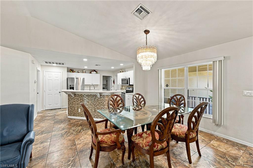 Vaulted ceilings, tiled flooring, chandelier lighting, and a kitchen pass-through with mosaic tile detailing