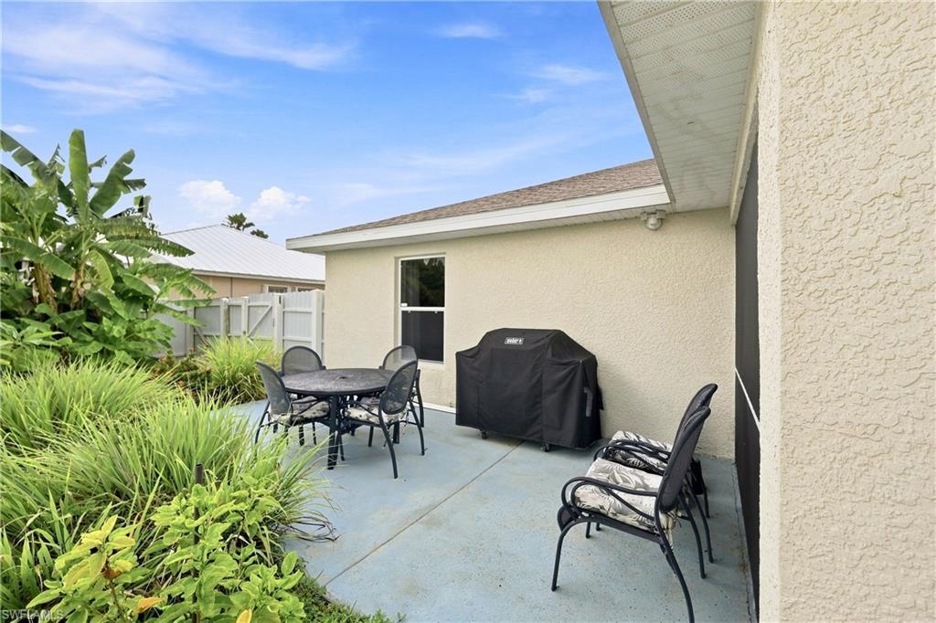 Concrete patio with textured stucco exterior, privacy fencing, and established perimeter landscaping