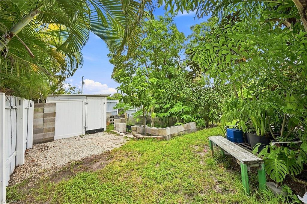 Expansive green space with mature trees, established landscaping, white privacy fencing, and a built-in storage shed