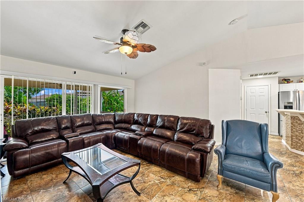 Vaulted ceiling with an integrated ceiling fan, ceramic tile flooring, and sliding glass doors