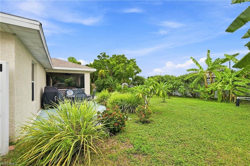 Spacious lawn area with mature landscaping, screened-in porch, and exterior privacy fence