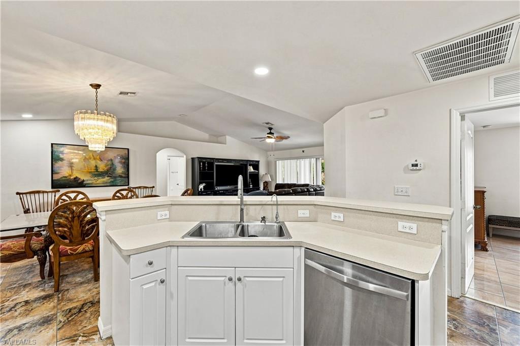 Kitchen with white cabinetry, light-toned countertop, and stainless steel dishwasher