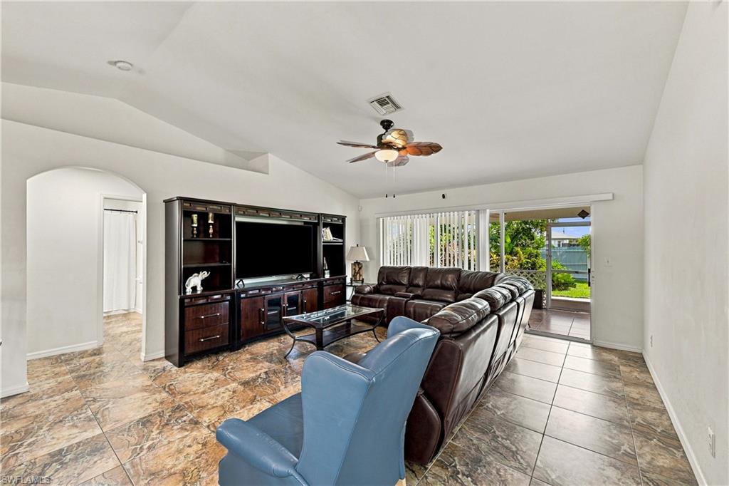 Vaulted ceilings, tiled flooring, arched doorway, and sliding glass doors to the exterior