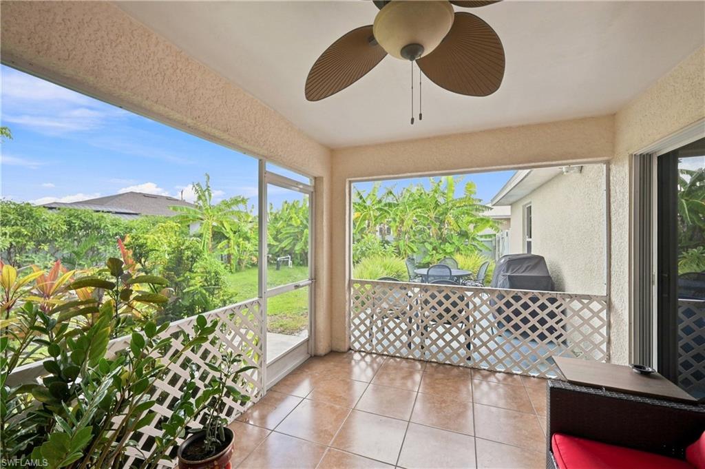Screened patio featuring tile flooring, a built-in ceiling fan, and lattice railing