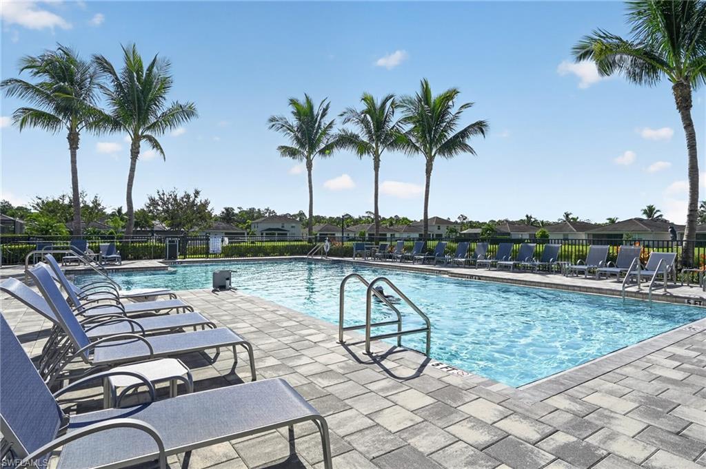 Swimming pool with paver decking, surrounded by a metal fence