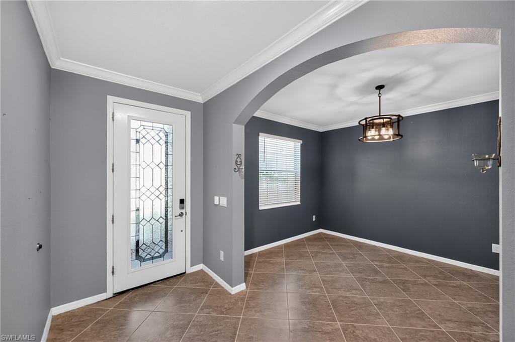 Entryway featuring a decorative glass panel door, crown molding, and large format tile flooring